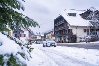 Snowy cityscape with residential buildings and parked car, Enzklösterle, district of Calw, Black