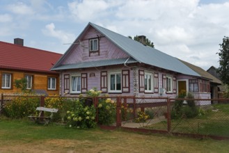 Wooden house with red roof in a rural setting, surrounded by garden and flowers, Wojszki,