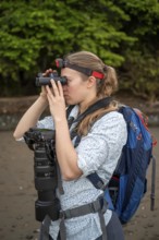 Tourist looking through binoculars, with headlamp and camera in the rainforest, Corcovado National