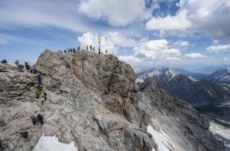 Tourists queue up for the summit of the Zugspitze, summit with golden summit cross, overtourism,