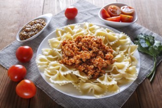 Farfalle bolognese pasta with minced meat on brown wooden background. close up