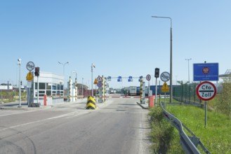 Customs station with open barrier and traffic signs on a sunny day, border from Poland to Ukraine,