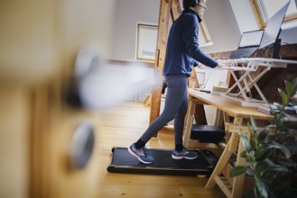 A woman walks on a walking pad at her desk while working from home. Berlin, 07.02.2024