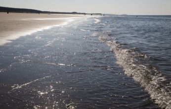 Contre jour waves reaching a sandy beach at Holkham, north Norfolk coast, England, United Kingdom,