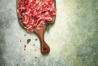 Prosciutto on a cutting board, top view, appetizer, breakfast, spices and herbs