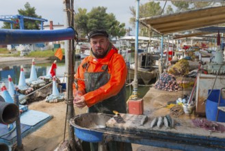 Fishermen standing in the harbour, dressed in orange, ready to sell fish, busy atmosphere at the