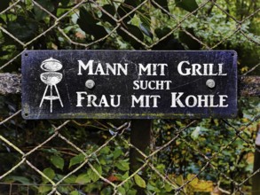 Sign on the fence with the slogan Man with barbecue seeks woman with coal, Traben-Trarbach, Middle