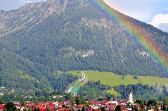 View over Oberstdorf with rainbow, behind it the Schattenberg with Schattenbergschanze, Oberallgäu,