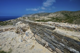 Ancient wall and ruins stretching over a hill, under a clear sky, Archaeological site, Vroulia,