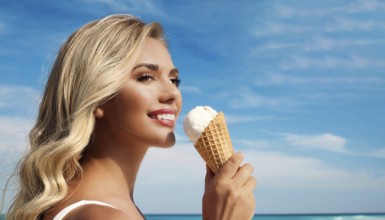 A blonde woman enjoys eating an ice cream in a cone