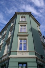 Historic building with mint facade and cream-coloured window frames under a clear blue sky with