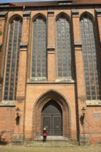 Large brick church with high windows, pointed arches, a person stands at the entrance, historic