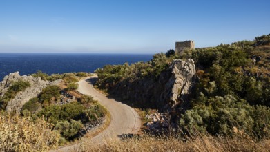 Winding road along the coastal cliffs with a view of the sea and a ruin, Mani Peninsula,