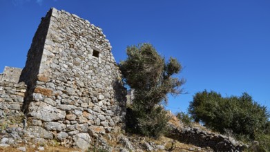 An abandoned ruin with stone walls under a clear blue sky, Flomochori, residential tower village,