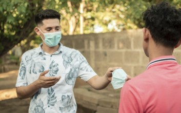 Young man sharing mask to another young man, young man giving a mask to another young man, concept