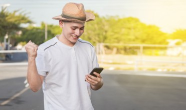 Man with winning gesture using cell phone in the street. Happy young man with winning gesture with