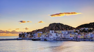 Picturesque coastal town at sunrise with colourful houses, sea and hills in the background,