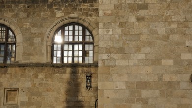 Old hospital, detail of a historic stone wall with windows and a lantern, showing Mediterranean