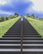 Steep metal stairs, brown, railing in the centre, green meadow to the left and right and green