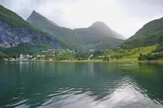 Mountainous landscape in a fjord reflecting the surrounding mountains and village, surrounded by