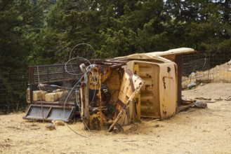 Overturned rusted vehicle in a wooded area, surrounded by twisted metal parts, wrecked vehicle,