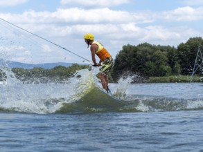 Sporty man with jump with wakeboard, water sports, water skiing and wake park