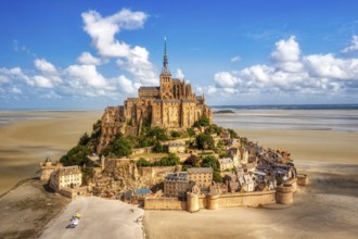 Island abbey majestically enthroned above sandy ground and under a clear sky, Le Mont-Saint-Michel