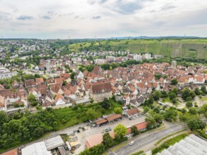 Urban settlement with tightly packed red roofs, surrounded by green hills and crossed by roads,