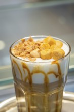 A drink with caramel and foam topping in a glass with a straw, autumn creations, Cafe Kuh,