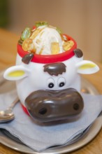 Ice cream in a cute cow cup with pieces of fruit, served on a table, autumn creations, Cafe Kuh,