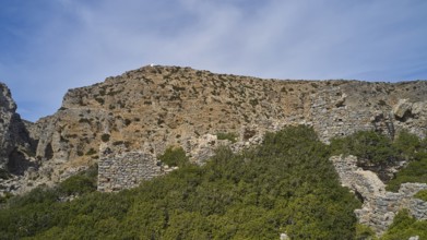 Palatia Beach, Palatia, Ancient ruins on a hill, surrounded by vegetation and under a blue sky,