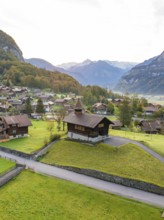 Picturesque Alpine village in a valley surrounded by green hills and majestic mountains, Lake