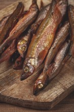 Cold smoked capelin, on a wooden chopping board, no people