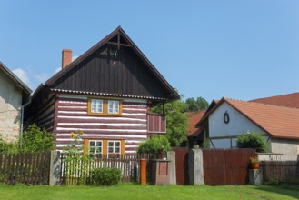 A traditional wooden house with residential facilities and a garden surrounded by a wooden fence,