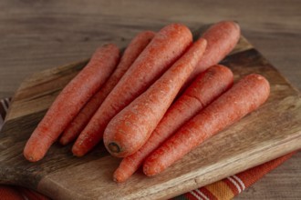 Fresh carrots on a chopping board, wooden table, raw carrots, no people