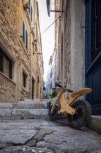 A child's bike stands in a sunny, historic alley with stone steps, Korcula, Croatia, Europe