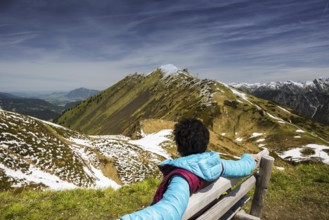 Woman, 50-55, sitting relaxed on a bench, sunbathing, behind her the Fellhorn, near Oberstdorf,