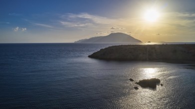 Sunset over the sea with a visible island and calm water, Kassos Island, drone shot, evening light,