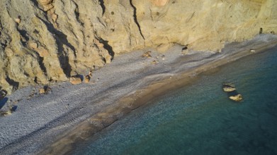 Rocky beach line with clear waves on a rocky coast, secluded and quiet, drone shot, evening light,