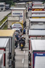 Motorcyclists squeeze past in the middle of the road between vehicles, in a 9 km long traffic jam