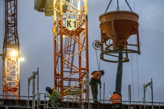 Concrete work, at dusk, on a large construction site building a residential and commercial complex,