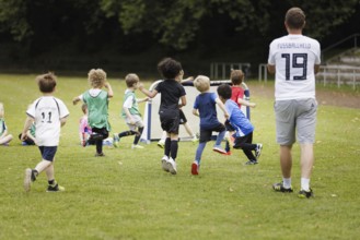 Volunteer coach trains children on the football pitch, Bonn, 19.06.2024