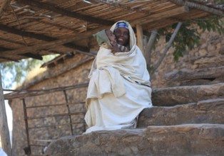 Yeha village, woman with child sitting on the stairs in the shade, Ethiopia, Africa