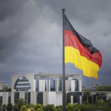 The flag of the Federal Republic of Germany flies in the wind in front of the Federal Chancellery