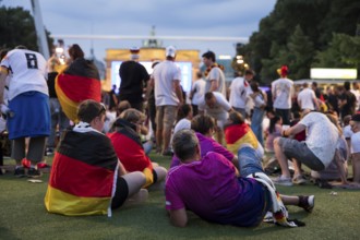 Fassball fans celebrate and gather information in the fan zone at the Brandenburg Tor after the