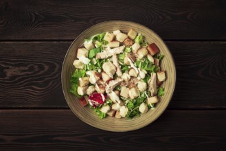 Fresh traditional Caesar salad, with chicken, on a wooden background, Top view, dark background,