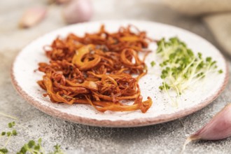 Fried Cordyceps militaris mushrooms on brown concrete background with microgreen, herbs and spices.