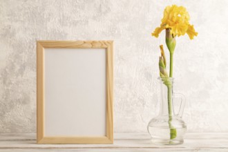 Wooden frame with yellow iris flower in glass on gray concrete background. side view, copy space,