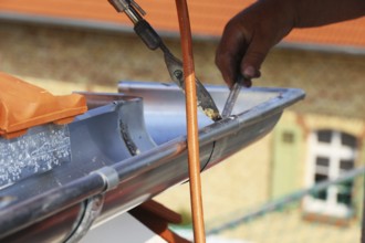 Roofer doing tinsmith work on a gutter