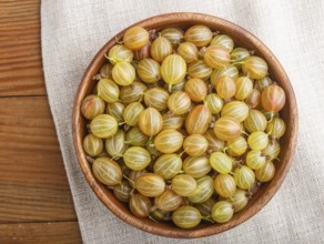 Fresh green gooseberry in wooden bowl on wooden background. top view, flat lay, close up